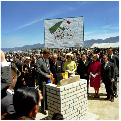 El presidente John F. Kennedy y el presidente Alberto Lleras Camargo de Colombia descubren una placa en una ceremonia de colocación de la primera piedra en el Proyecto de Vivienda de Ciudad Techo en Bogotá, Colombia, que marca la construcción de viviendas y escuelas construidas a través de la Alianza para el Progreso. De izquierda a derecha: presidente Kennedy, presidente Lleras, primera dama Jacqueline Kennedy, varias personas no identificadas, agente del Servicio Secreto de la Casa Blanca Gerald A. “Jerry” Behn, al fondo (a la izquierda del presidente Kennedy), 17 de diciembre de 1961