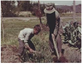 Un adulto y un infante preparando la tierra para la siembra